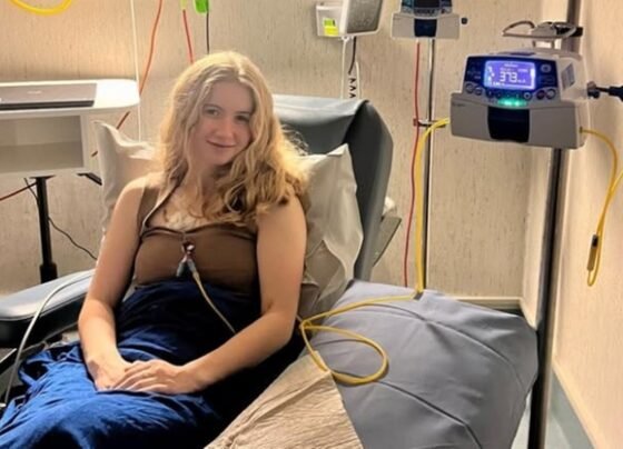 Imagem mostra Dominique McShain, uma mulher jovem, branca e loira, sentada em uma maca de hospital - Metrópoles