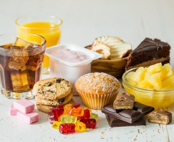 Foto colorida de balinhas, cupcakes, suco, refrigerante, bolo e guloseimas - Metrópoles