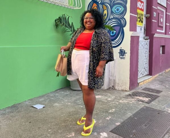 Mulher em pé sorrindo em rua - Metrópoles