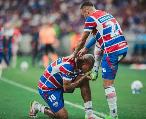 Imagem coloria de Deyverson beijando a chuteira de Breno Lopes, em jogo do Fortaleza - metrópoles
