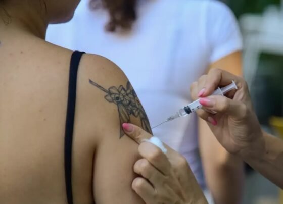 foto colorida de mulher tatuada (pessoa é vista de costas) sendo vacinada contra a gripe - Metrópoles - Vacinas imunização diabetes