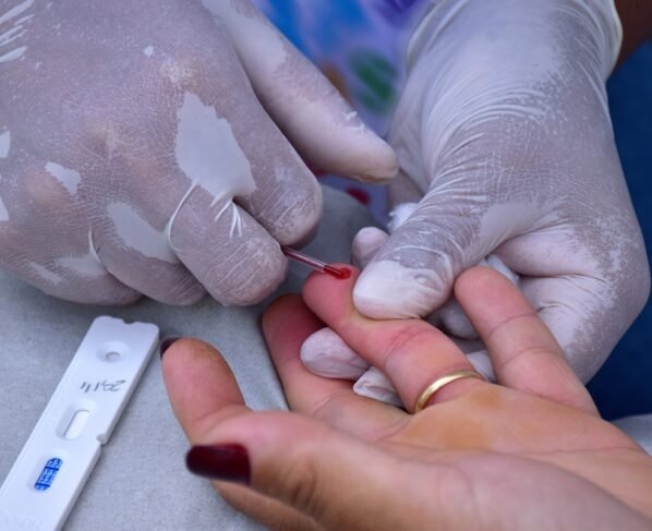 Enfermeira realizando teste rápido para AIDS, HIV, sífilis e hepatite em mulher.