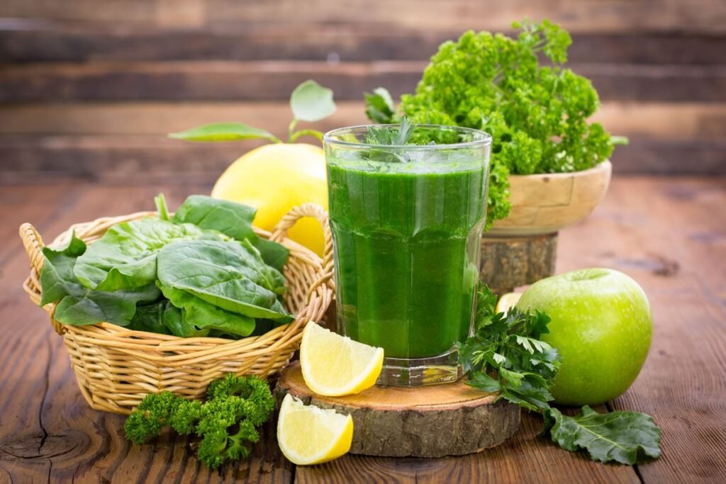 Foto de suco verde ao lado de um limão fatiado, couve, maçã verde e laranja - Metrópoles - imunidade