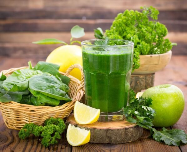 Foto de suco verde ao lado de um limão fatiado, couve, maçã verde e laranja - Metrópoles - imunidade