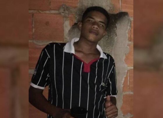Jovem desaparecido é encontrado morto no DF. Pheterson Rodrigues estava desaparecido e a família bsucava por ele. Jovem com camisa preta listrada de branco. Ao fundo, um muro de tijolos - Metrópoles