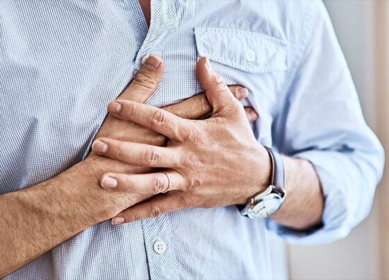 Foto de um homem com camisa azul pressionando o peito - Metrópoles
