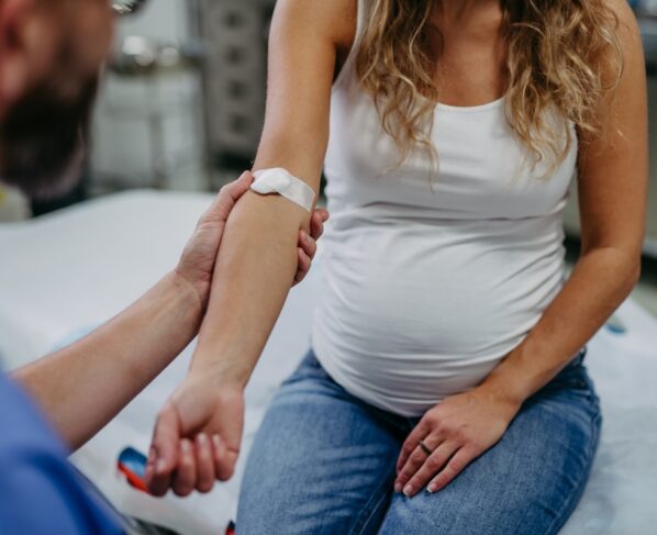 Ginecologista obstetra coletando amostra de sangue de gestante como parte do pré-natal. Gestante em consulta de acompanhamento gestacional no consultório médico. Metrópoles