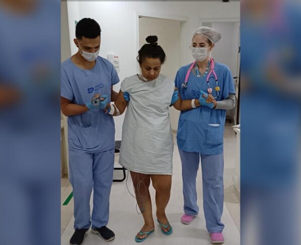 Imagem mostra mulher em hospital sendo amparada por dois profissionais de saúde - Metrópoles