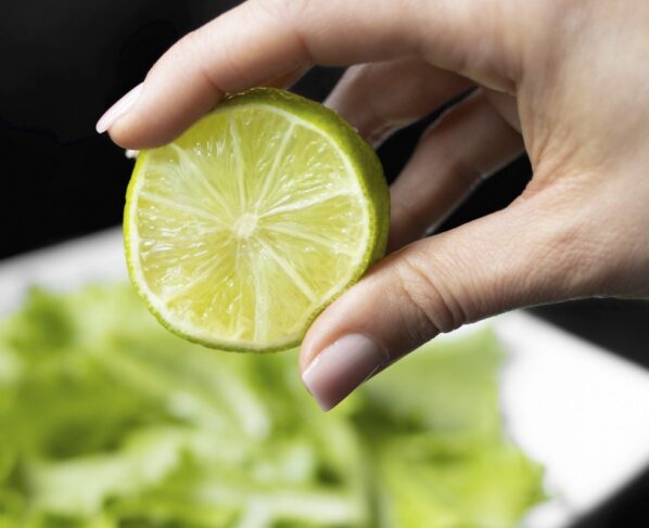 Foto colorida de mão segurando metade de um limão - Chá anti-inflamatório alivia dor de garganta e reforça imunidade