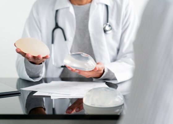 Close-up de um cirurgião plástico comparando dois tipos de implantes mamários em seu consultório - conceitos de saúde e medicina. Metrópoles