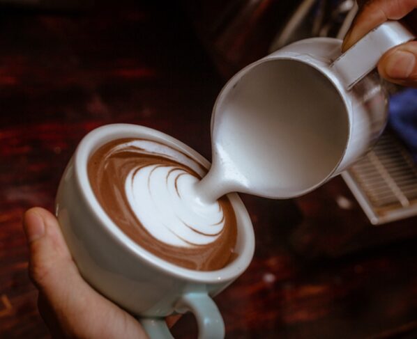 Foto colorida com mãos de homem fazendo um cappuccino - Metrópoles