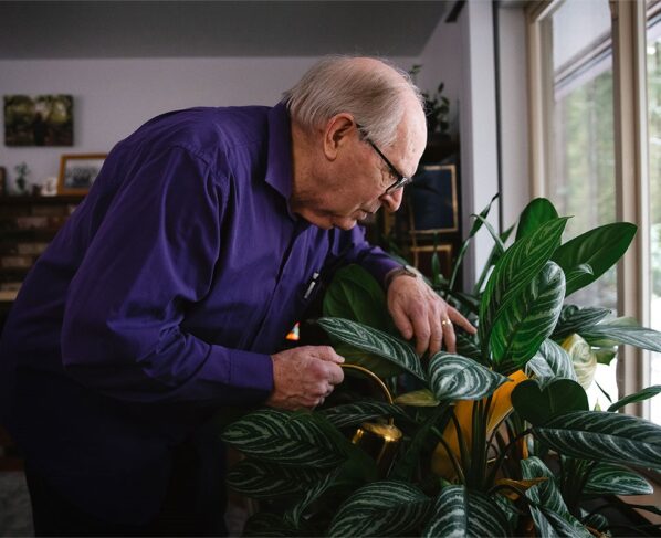 Imagem colorida mostra homem branco idoso de óculos com cabelos mais ralos regando as plantas - Metrópoles