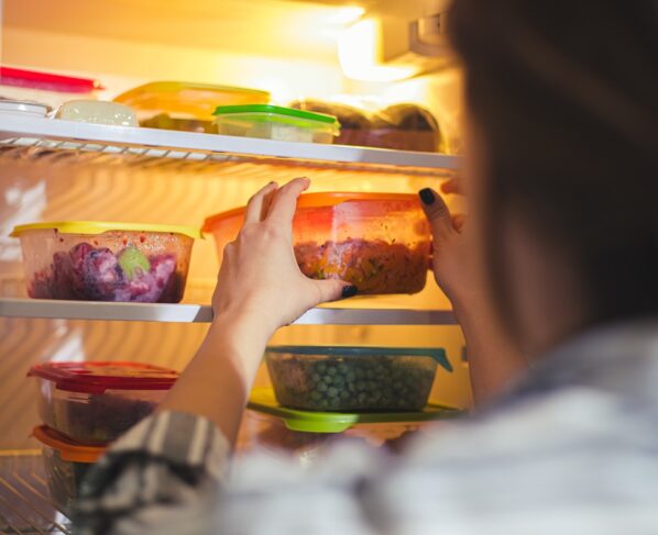 Imagem mostra mulher guardando potes de vidro tampados com comida na geladeira - Metrópoles