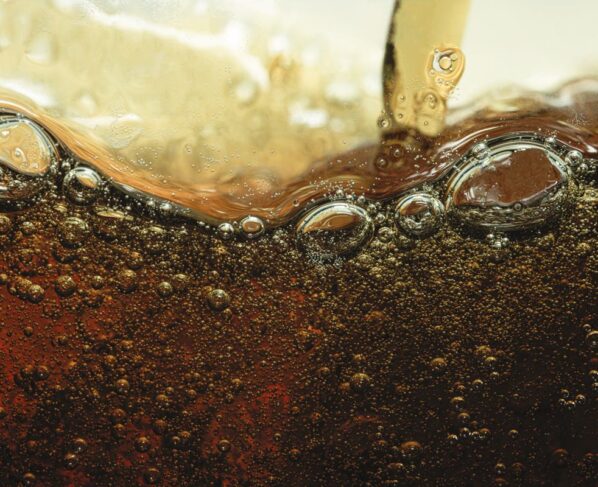 Imagem mostra refrigerante escuro com bolhas visto de perto - Metrópoles