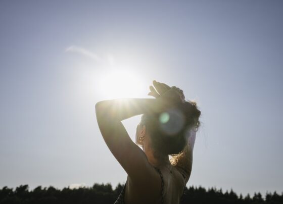 Imagem mostra mulher com os braços para cima recebendo a luz do sol - Metrópoles