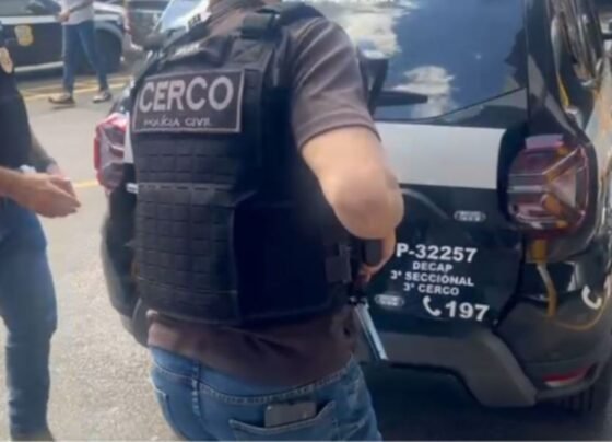 Imagem colorida mostra policiais em volta de carro - Metrópoles