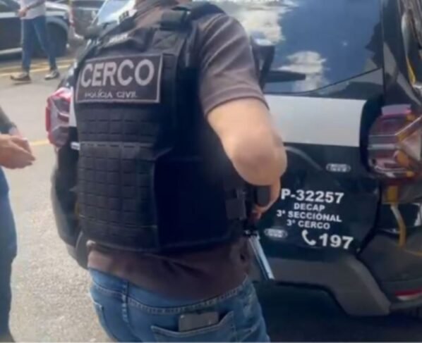 Imagem colorida mostra policiais em volta de carro - Metrópoles