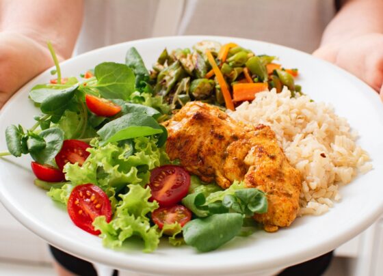 Foto colorida de pessoa segurando um prato de comida saudável - Exagerou? Hepatologista conta o que é bom para desintoxicar o fígado - Metrópoles