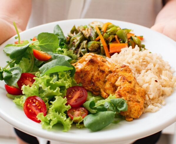 Foto colorida de pessoa segurando um prato de comida saudável - Exagerou? Hepatologista conta o que é bom para desintoxicar o fígado - Metrópoles