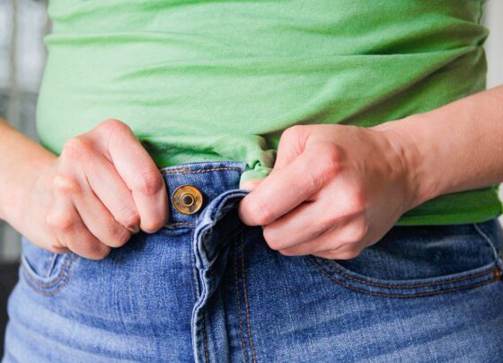 Mulher tenta fechar calça jeans - Metrópoles