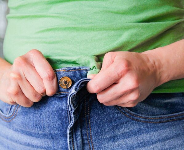 Mulher tenta fechar calça jeans - Metrópoles