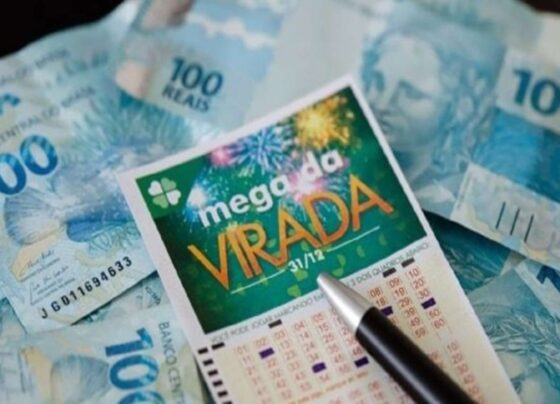 Imagem colorida de cartela de aposta da mega da virada acima de notas de R$ 100 - Metrópoles