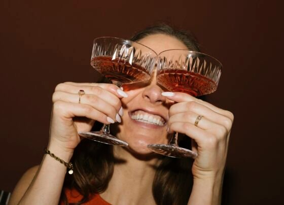Foto colorida de mulher segurando duas taças perto dos olhos - Metrópoles