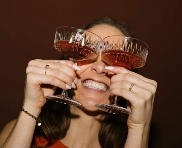 Foto colorida de mulher segurando duas taças perto dos olhos - Metrópoles