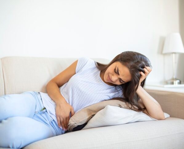 Foto colorida de mulher jovem sofrendo com intestino preso - Nutricionista lista melhores alimentos para quem tem intestino preso - Metrópoles