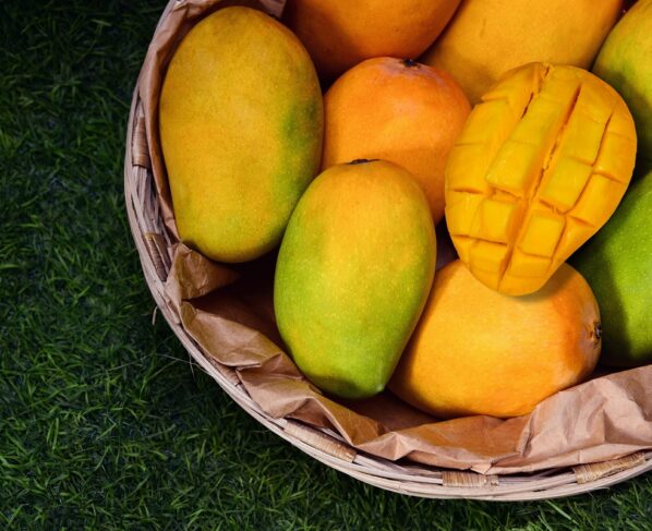 Imagem mostra várias mangas dentro de um recipiente de madeira em cima de um gramado. Metrópoles