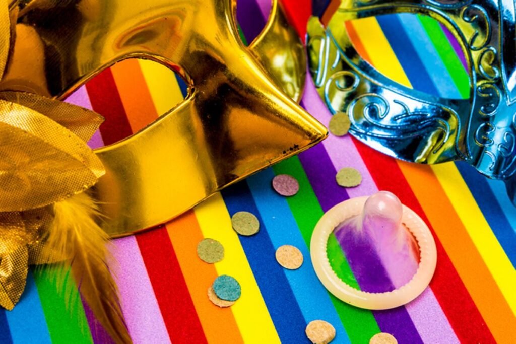 Foto com duas máscaras de Carnaval, camisinha e confete - Metrópoles - prevenção às ISTs