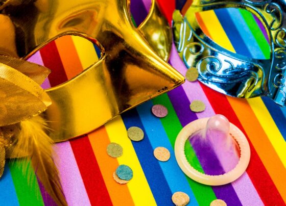 Foto com duas máscaras de Carnaval, camisinha e confete - Metrópoles - prevenção às ISTs