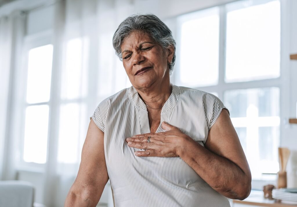 Foto colorida de mulher com a mão no peito - Cardiologistas explicam quais são os primeiros sintomas do infarto - Metrópoles