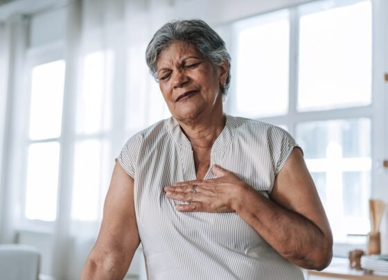 Foto colorida de mulher com a mão no peito - Cardiologistas explicam quais são os primeiros sintomas do infarto - Metrópoles