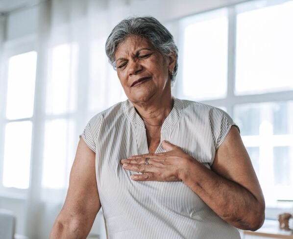 Foto colorida de mulher com a mão no peito - Cardiologistas explicam quais são os primeiros sintomas do infarto - Metrópoles