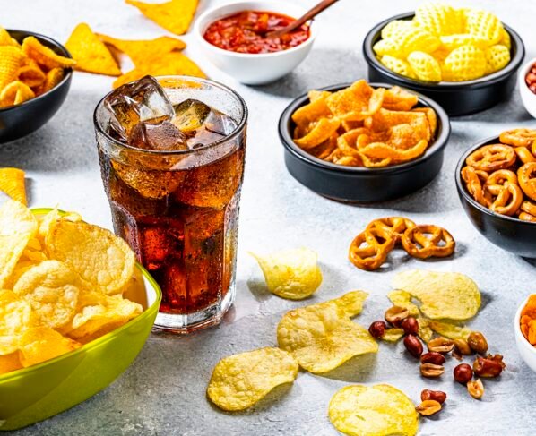 Comida não saudável: copo de refrigerante e diversos salgadinhos - Comida remosa existe ou é mito? Entenda o que a ciência sabe sobre - Metrópoles