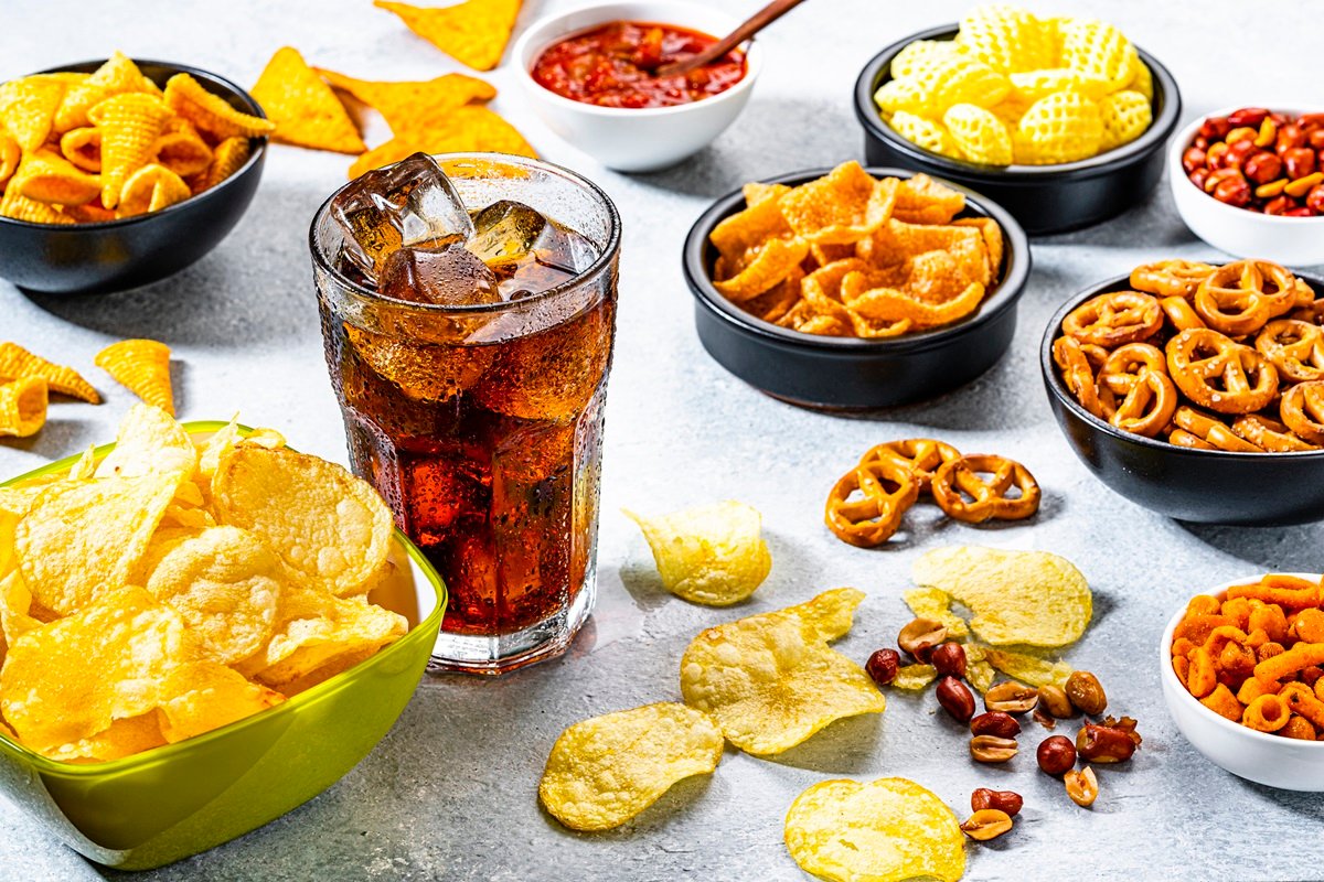 Comida não saudável: copo de refrigerante e diversos salgadinhos - Comida remosa existe ou é mito? Entenda o que a ciência sabe sobre - Metrópoles