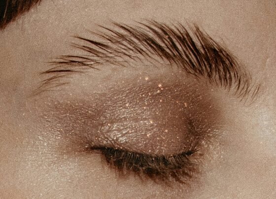 Imagem mostra mulher maquiada de olho fechado e sobrancelha penteada para cima - Metrópoles