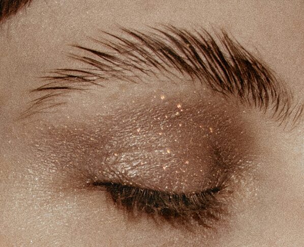 Imagem mostra mulher maquiada de olho fechado e sobrancelha penteada para cima - Metrópoles