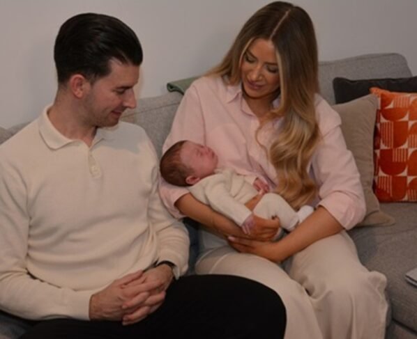 Foto colorida de familia com bebê recém-nascido no colo, resultad de transplante de útero em sucedido - Metrópoles.