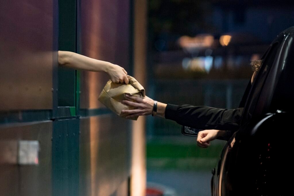Foto colorida de duas pessoas no drive-thru - Metrópoles.
