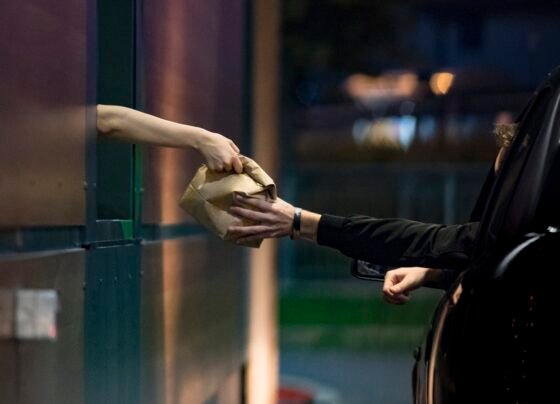 Foto colorida de duas pessoas no drive-thru - Metrópoles.