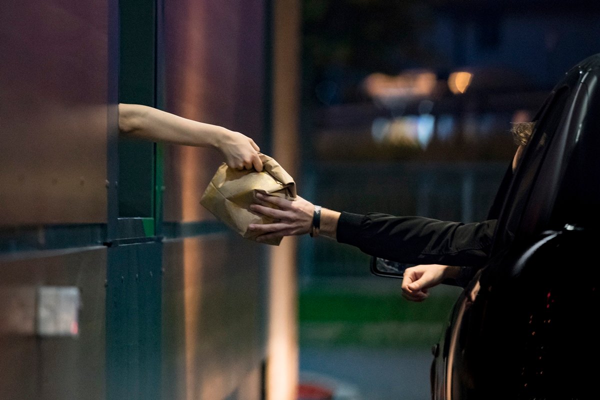 Foto colorida de duas pessoas no drive-thru - Metrópoles.