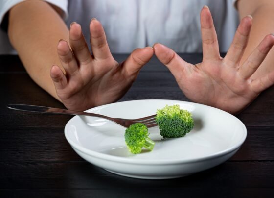 Mãos de mulher empurrando prato com brócolis - Metrópoles