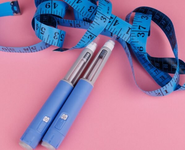 Foto colorida com fundo rosa de canetas emagrecedoras de cor azul - Metrópoles.