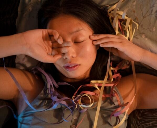 Foto colorida de mulher deitada dormindo em meio a confetes