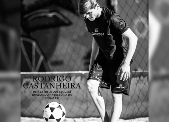 foto em preto e branco de adolescente se preparando pra chutar bola em campo de areia - metrópoles