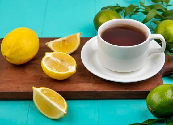 Xícara de café em cima de tábua de madeira ao lado de limões
