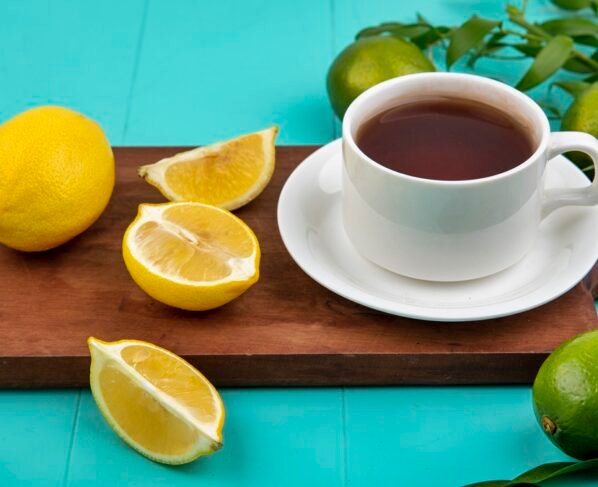 Xícara de café em cima de tábua de madeira ao lado de limões