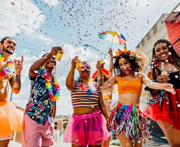 Foto colorida de grupo de foliões em Carnaval brindando - Metrópoles